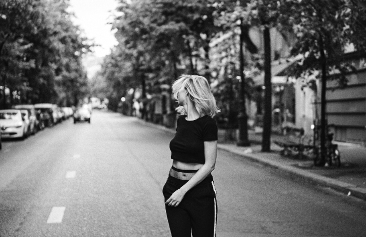 Black and white image. Girl walking on the road looking behind.