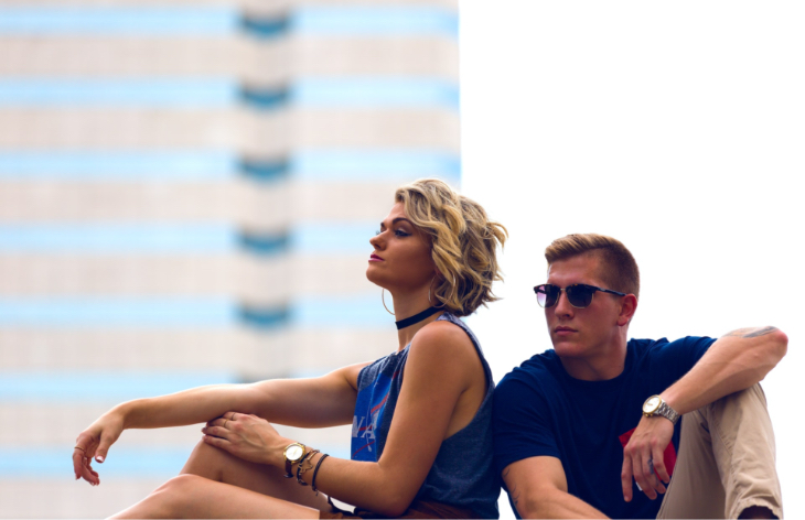 Man and woman sit back to each other, thinking and looking at different sides.