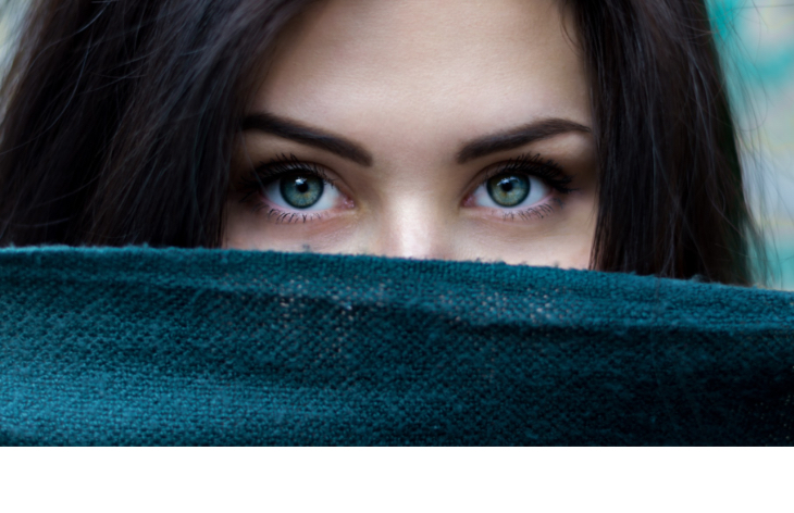 Girl with big green eyes with a scarf covering her nose and mouth.