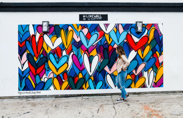 Woman standing and looking at the love wall full of hearts.
